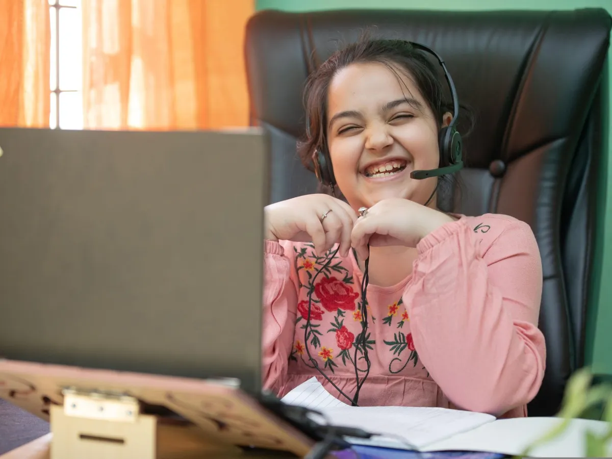 A girl laughing with her headset on during a live online class