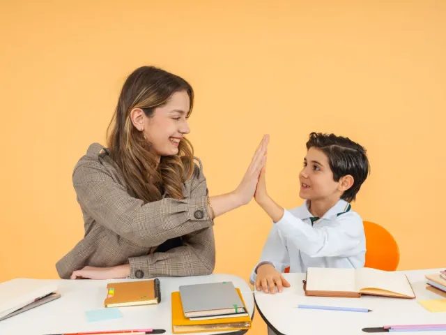 A friendly teacher high-fiving a student
