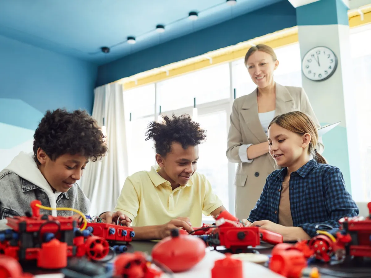 Kids building a robot together while their teacher looks on
